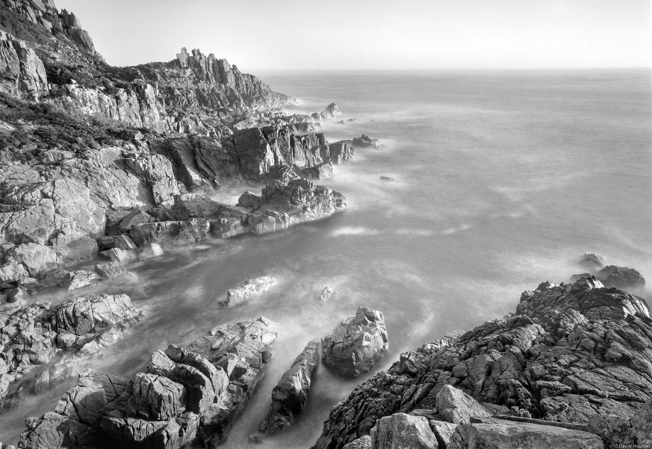 Looking down on a rocky bay, cliffs and the ocean at sunrise