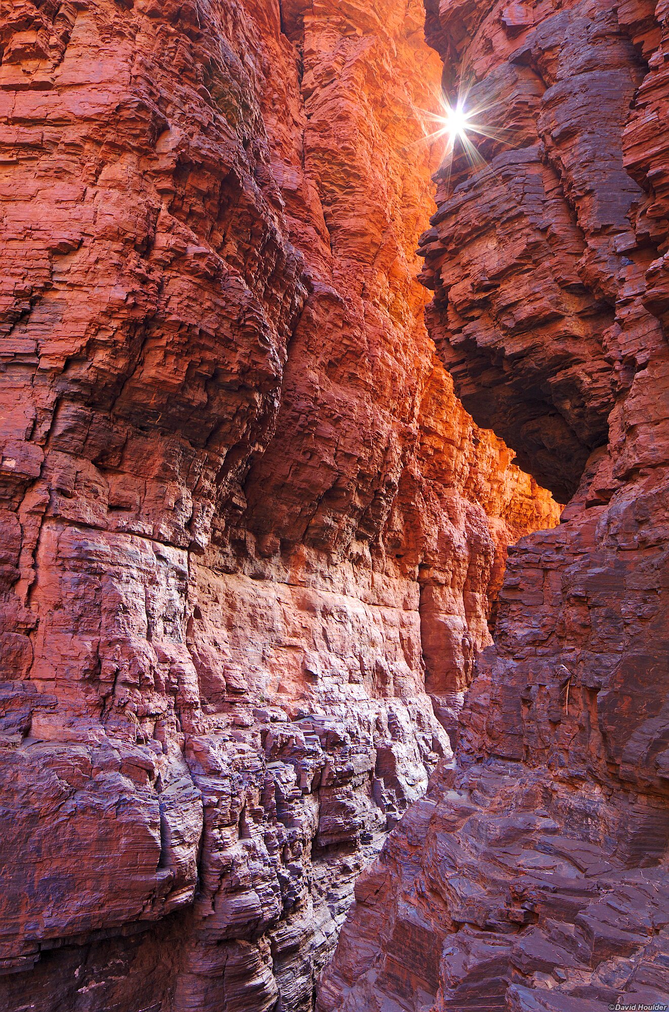 A narrow ravine with the sun peeking through the gap