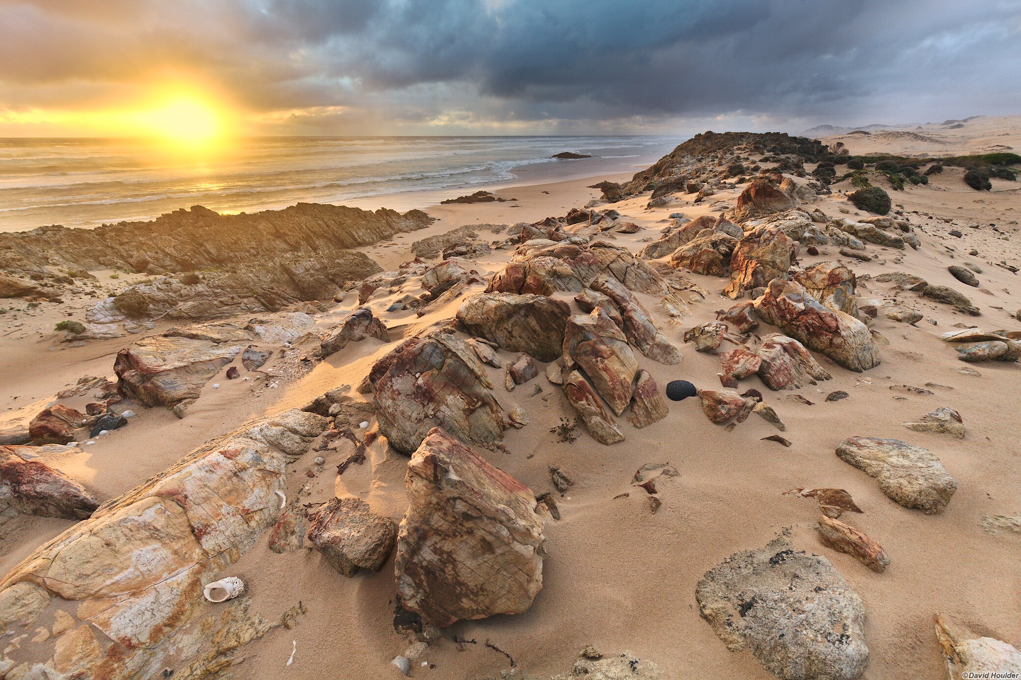 Rocky outcrop protruding from the sand beside the ocean