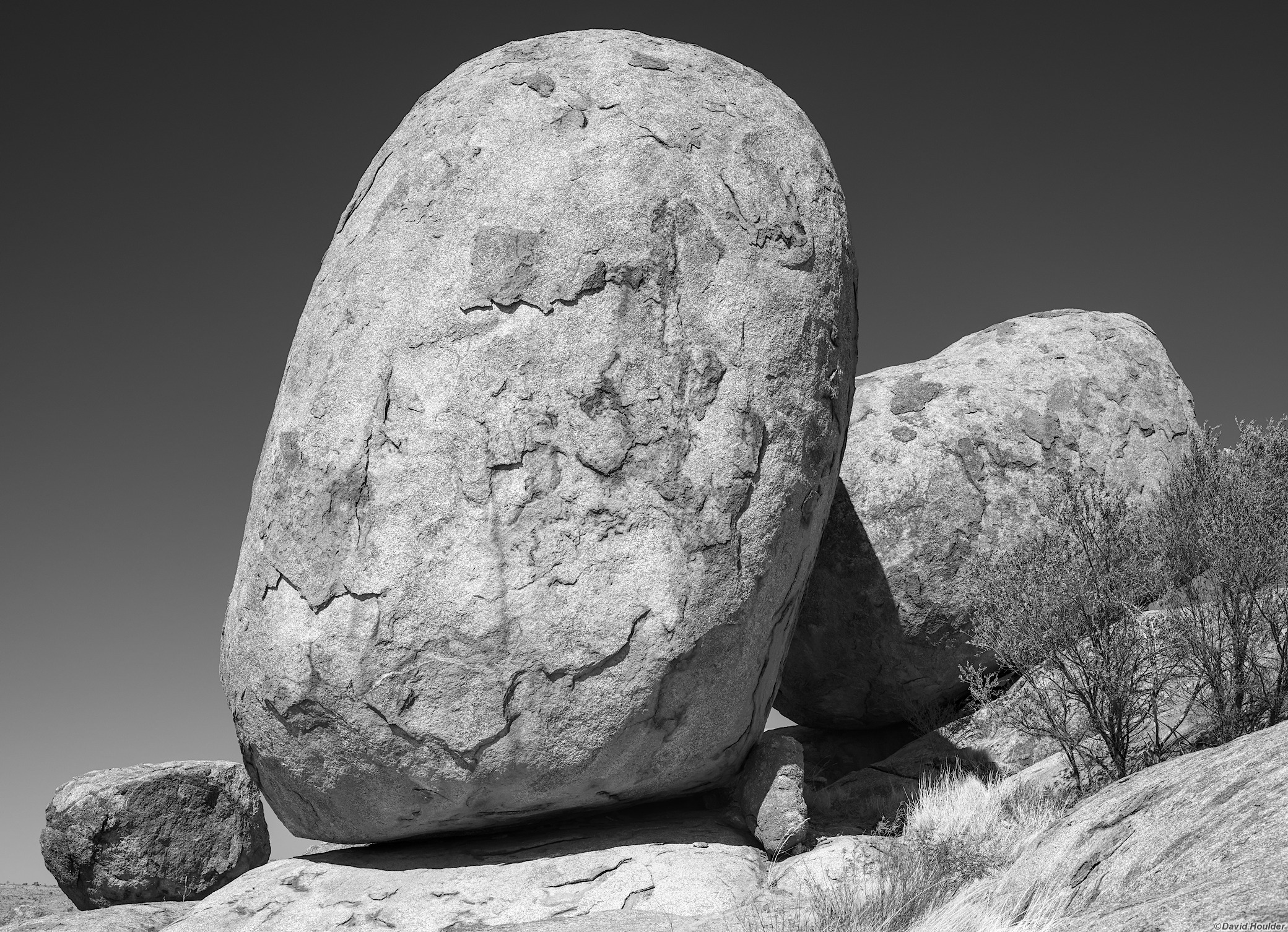 A large granite boulder with two smaller boulders either side lit by direct sunlight