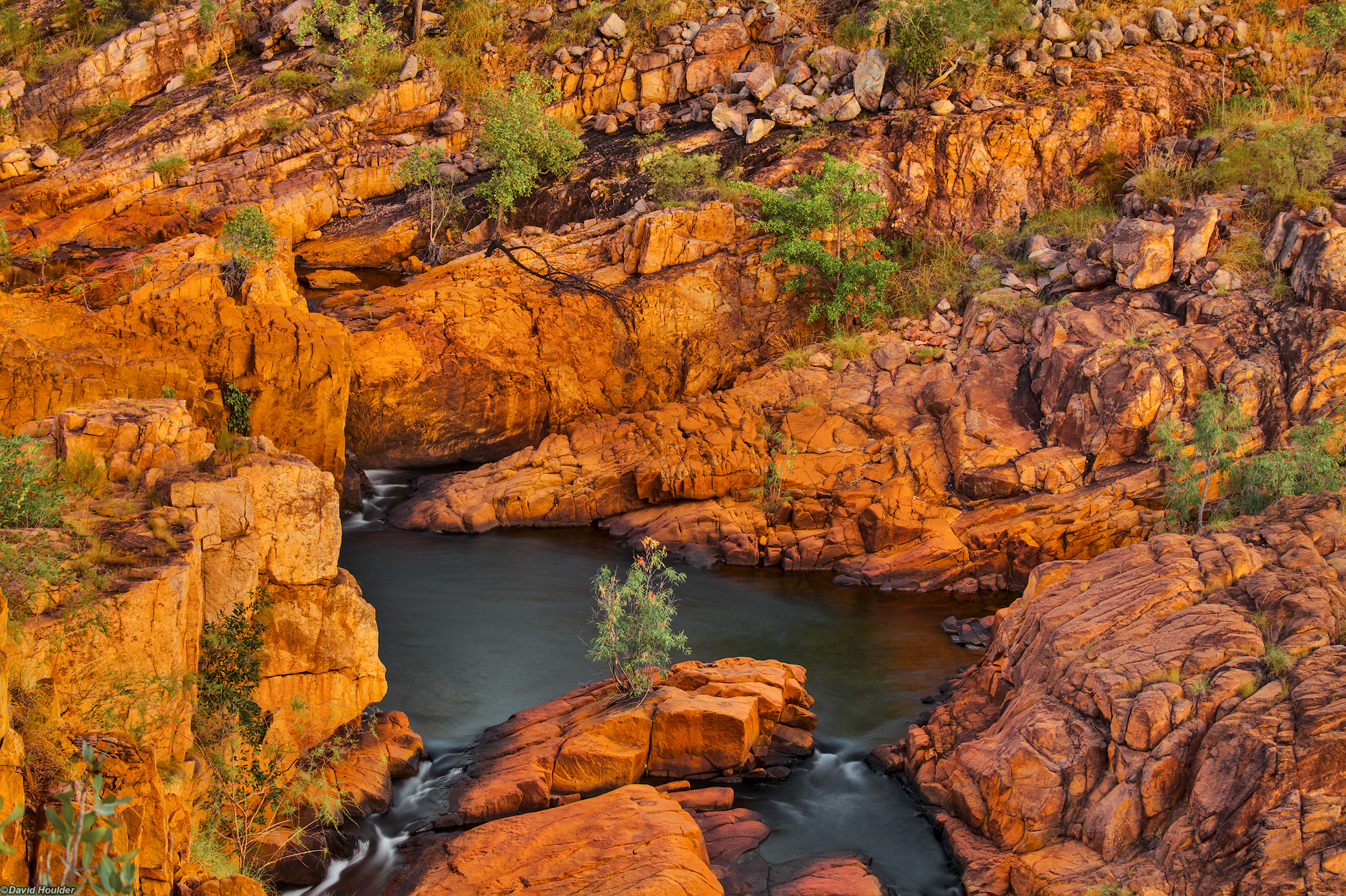 A natural pool surrounded by rocky outcrops and sparse vegetation