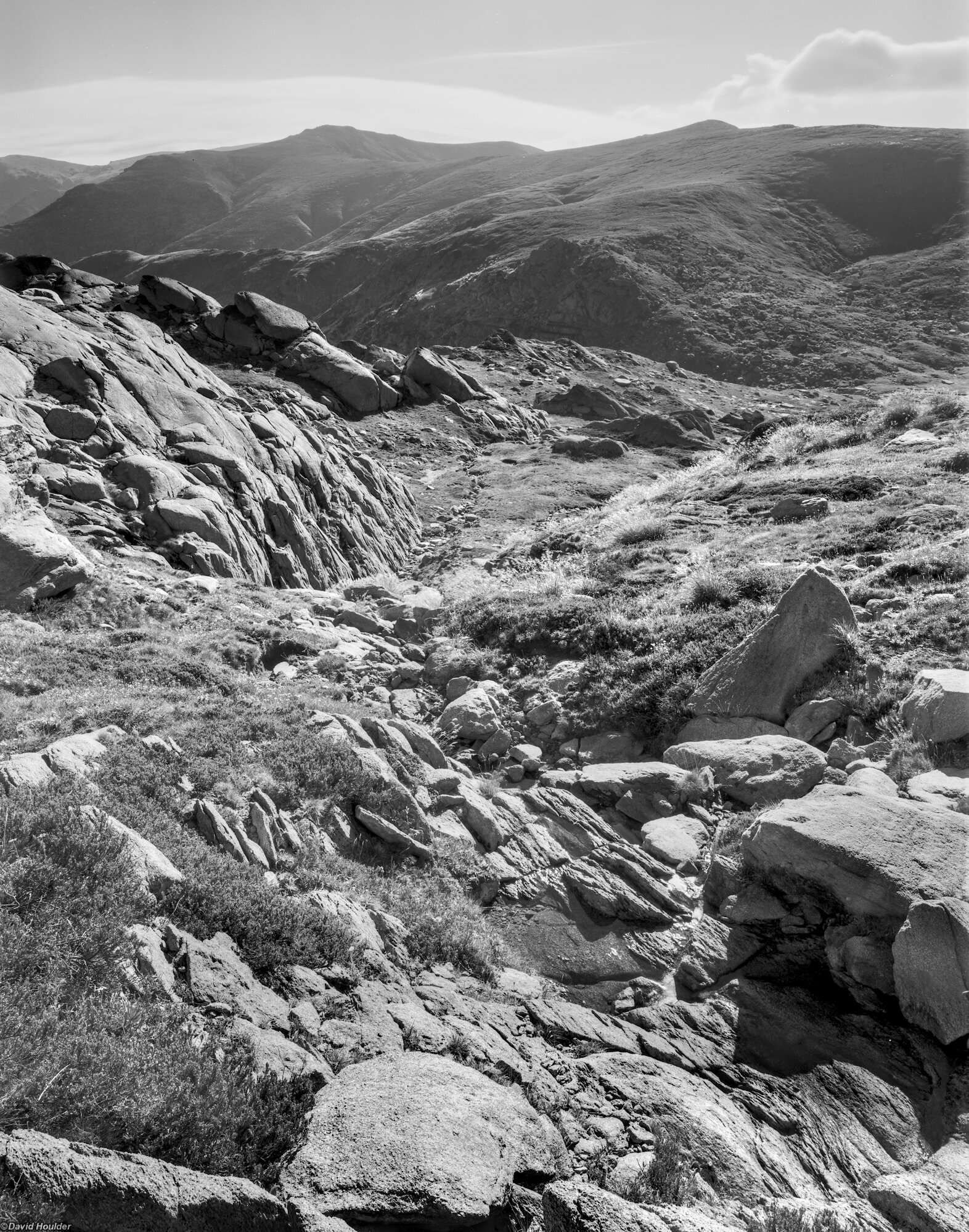 Looking down a rocky creek-bed to a valley in the distance